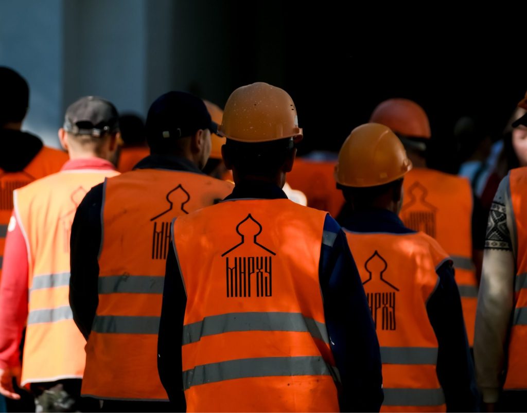 Équipe en gilets de sécurité et casques de chantier réunie pour une causerie sécurité